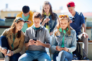 happy teenage friends with smartphones outdoors