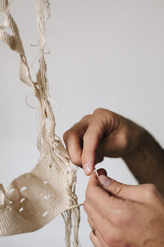 An artist working on an art piece, creating an object with thread. 
