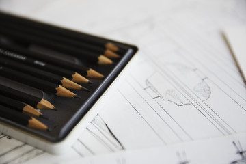 Close up of design drawings for furniture and a tray of pencils.