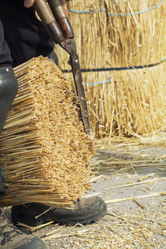 Close up of a thatcher cutting a yelm of straw with a pair of shears.
