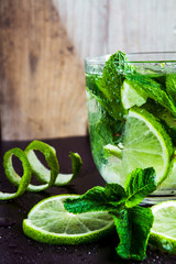 Green limes with mint and water drops on black background