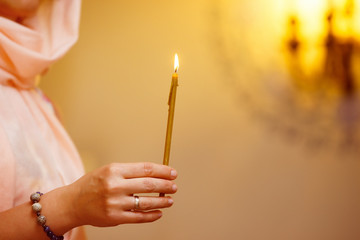 Closeup hand holding candle at Christian church background