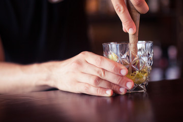 Bartender is making cocktail at bar counter at night club, toned
