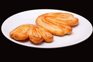 Two palmier biscuits with sugar on the white plate close-up