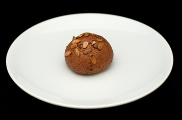 Rye sandwich bun with pumpkin seeds on white plate 