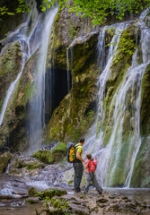 Obraz premium Father and daughter close to a waterfall in a forest