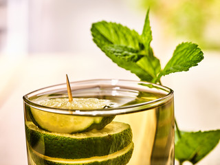 Alcohol drink. On wooden boards top of glass with alcohol green transparent drink. Drink two hundred sixty-eight cocktail green tea decorated with lime and mint leaf. Country life. Light background.