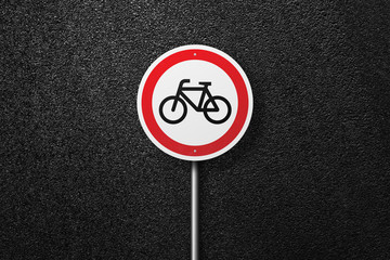 Road sign of the circular shape with a picture of the bike on a background of asphalt. The texture of the tarmac, top view.
