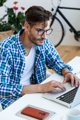 Handsome young man working with laptop at home.
