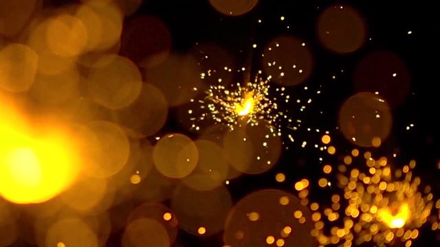 Three orange sparklers against dark background. Super slow motion shallow focus video, 500 fps