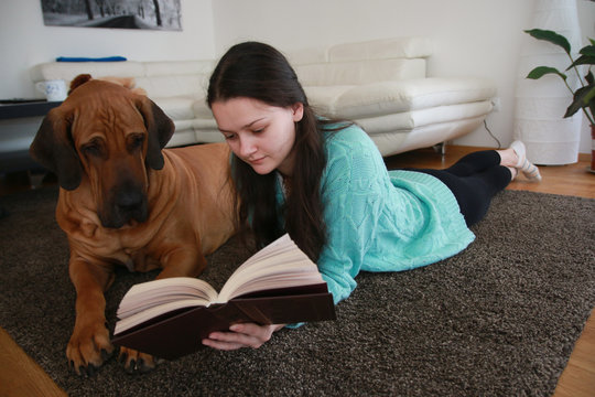 Young woman reading the book with dog