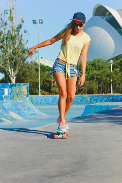 Beautiful girl riding on a skateboard in sunny weather