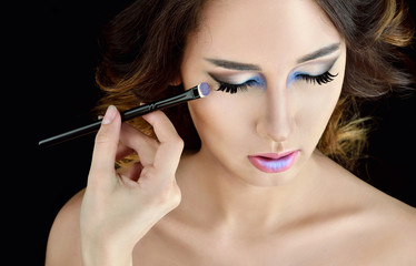 Obraz premium Wedding makeup artist making a make up for bride. Beautiful sexy model girl indoors. Beauty woman with curly hair. Female portrait. Bridal morning of a cute lady. Close-up hands near face