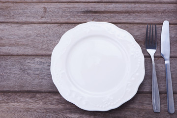 Top view of empty plate with fork and knife on a wooden table. 