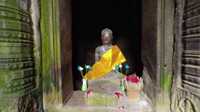 Approaching shot of a sacred, sculpted Buddha image inside the ancient, mossy walls of Bayon Temple, near Siem Reap, Cambodia. FullHD 1080p video