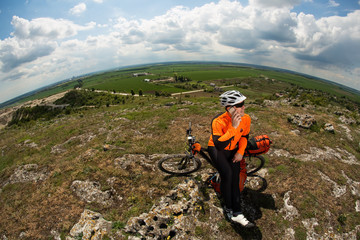 Obraz premium Young Cyclist In Orange Shirt Checks His Phone