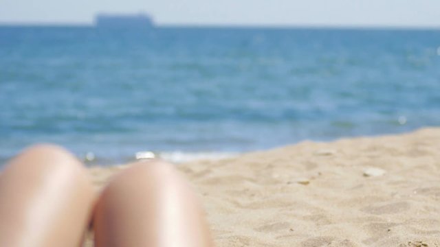 Beautiful Tanned Women's Legs at the Beach Sunbath