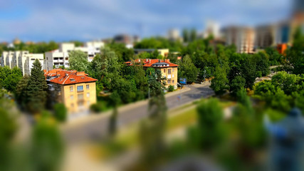 Small toy like miniature tilt-shift effect photo of a residential housing along a boulevard as a green system