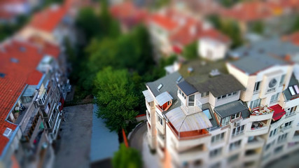 Toy like miniature tilt-shift effect photo of a residential housing top roof terraces and trees in-between the buildings 