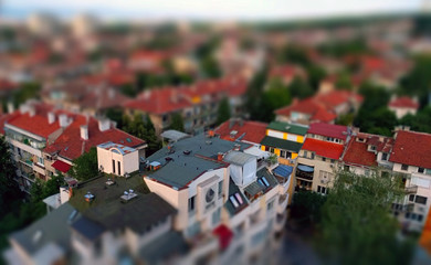 Small toy like miniature tilt-shift effect photo of a residential housing top roof terraces and trees in-between the buildings 