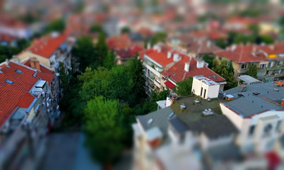 Cute toy like miniature tilt-shift effect photo of a residential housing top roof terraces and trees in-between the buildings 