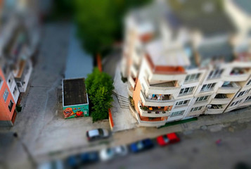 Cute toy like miniature tilt-shift effect photo of a street with residential housing and parked cars near garage cell