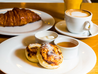russian cheesecakes with a croissant and cappuccino
