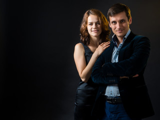 The girl in black skin-tight dress hugging a guy in  velvet jacket