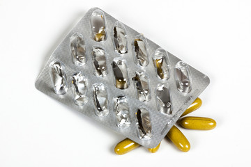 Empty Blister Pill Pack above Mustard Colored Capsules