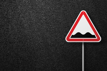 Road sign of the triangular shape on a background of asphalt. Rough roads. The texture of the tarmac, top view.
