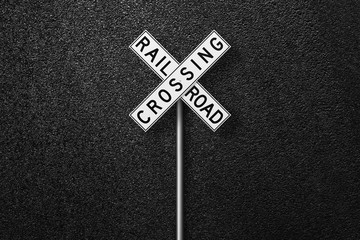 Road sign on a background of asphalt. RAIL ROAD CROSSING. The texture of the tarmac, top view.