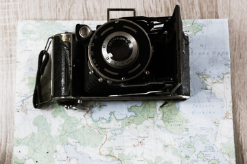 Old photo camera and paper map. Bleach
