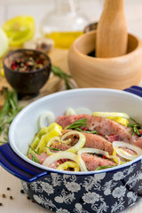 Meat in a pan with onions, spices and rosemary.