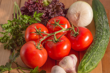 vegetables lying on wooden surface. branch of tomatoes and assorted vegetables