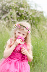 child smelling pink rose