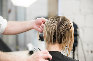 Obraz na płótnie Canvas Hairdresser cutting client's hair in salon with electric razor closeup.