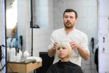 male hairdresser puts woman's hair in a hairdressing salon