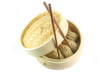 Ravioli cinesi al vapore in un canestro e bacchette