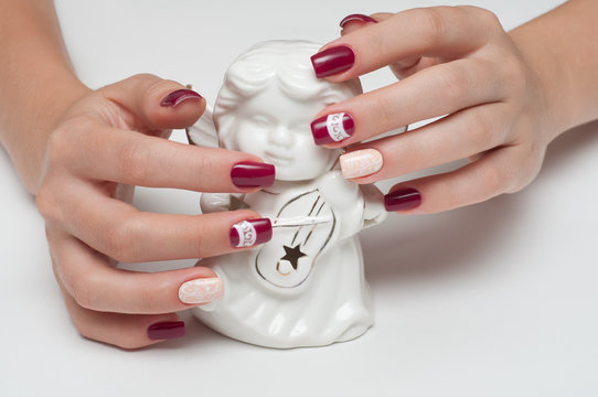square burgundy manicure with openwork and an angel in the hands of