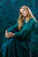 blonde girl on a green background in a long green dress