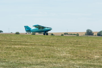 Fototapeta na wymiar Small tow plane landing on a grassy airfield