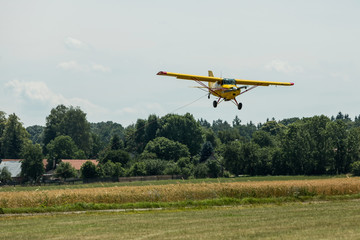 Fototapeta na wymiar Small tow plane landing on a grassy airfield