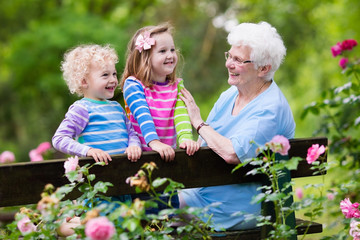 Grandmother and kids sitting in rose garden