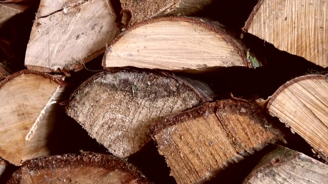 Footage of large pile of chooped wood pieces piled neatly onto one eachother warm dark typical brown wood color stacked wood is ready and dried for use in fireplace at colder winter months 4k quality