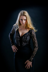 blonde girl on a black background in a dark guipure dress