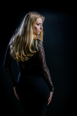 blonde girl on a black background in a dark guipure dress