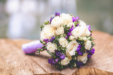 Wedding bouquet with white and violet flowers on nature wooden background. wedding concept