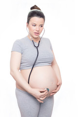 Pregnant woman listening her belly with a stethoscope 