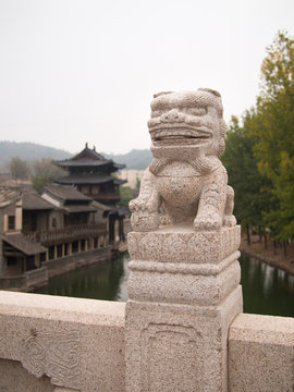 Statue of Chinese dragon on a background of the temple with water and trees
