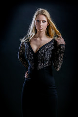 Fototapeta premium blonde girl on a black background in a dark guipure dress